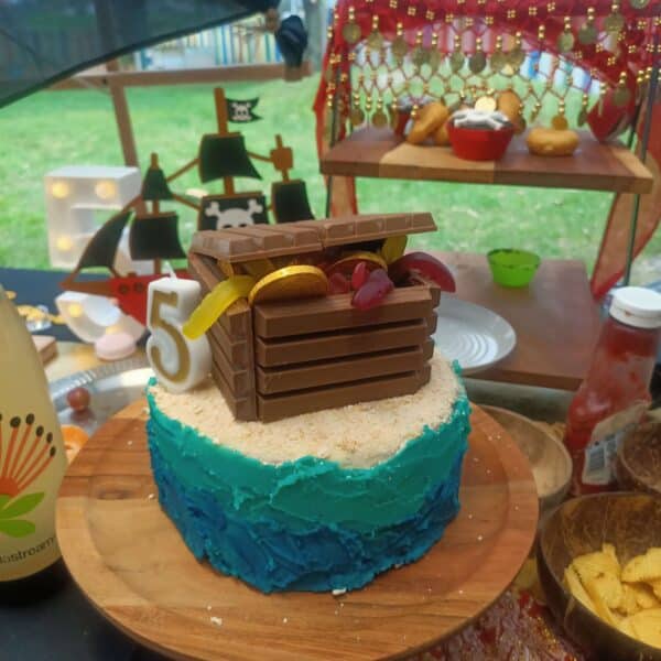 an image of a birthday cake with a treasure chest on top. The background is a childs pirate party