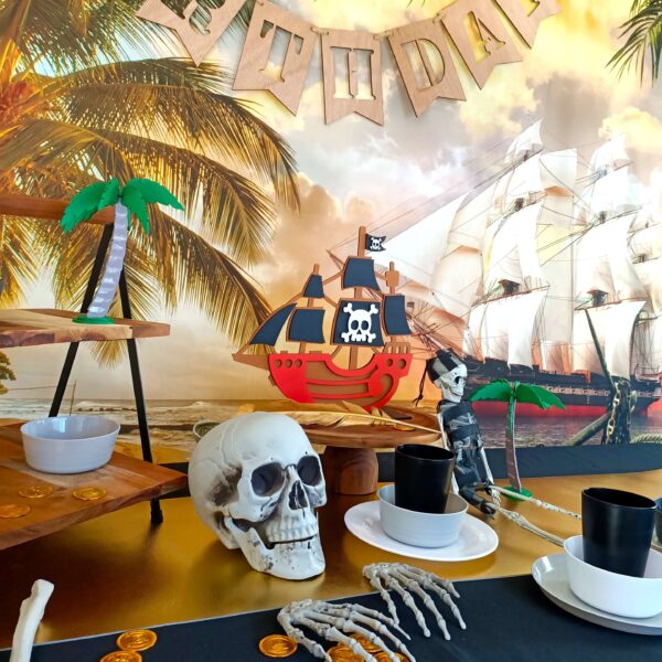 A pirate party table set up with black table cloth, skeletons, gold and plates